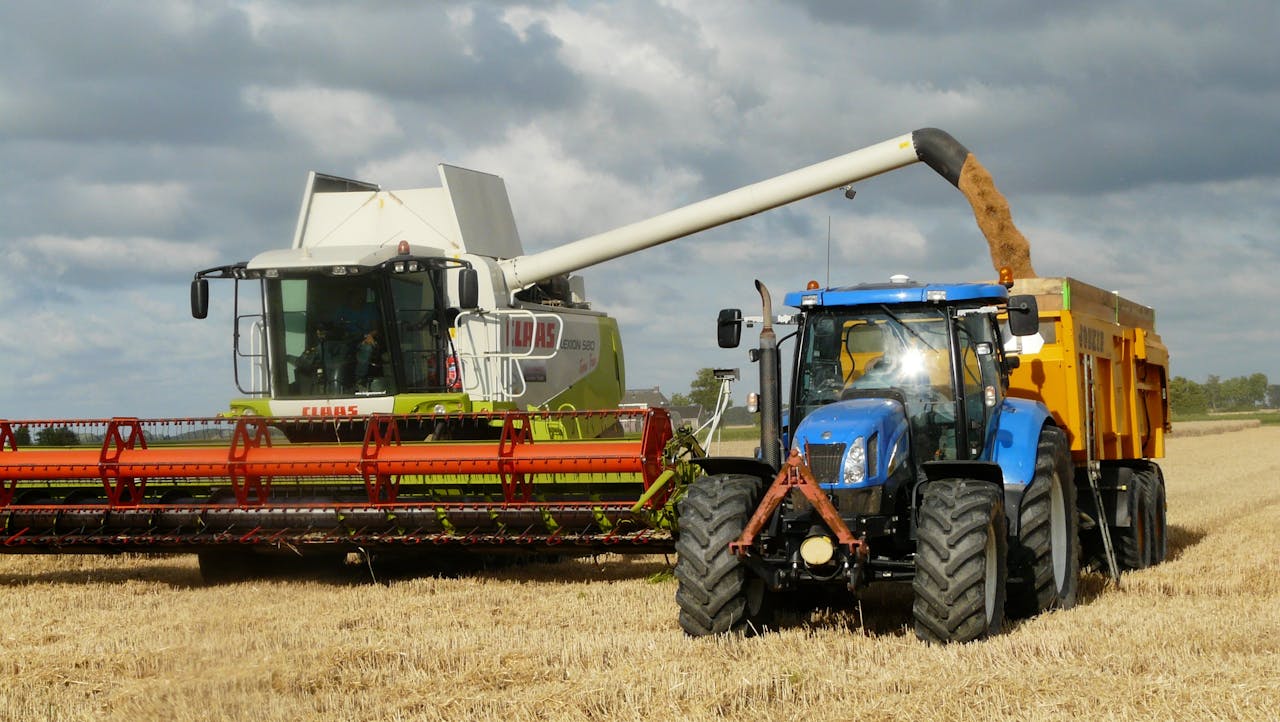 Blue Tractor Next to White Farm Vehicle at Daytime